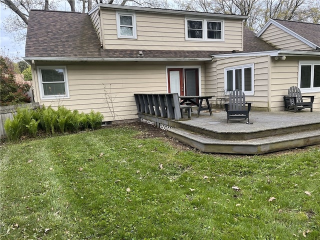 rear view of house with a wooden deck, a yard, and a shingled roof