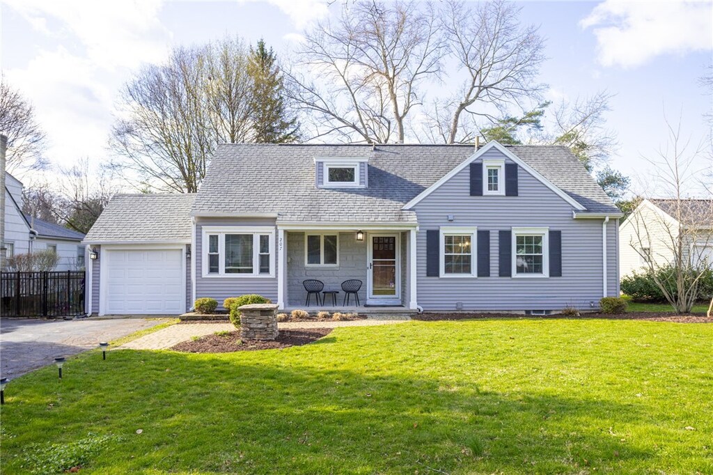 new england style home featuring driveway, a porch, a front lawn, and a shingled roof