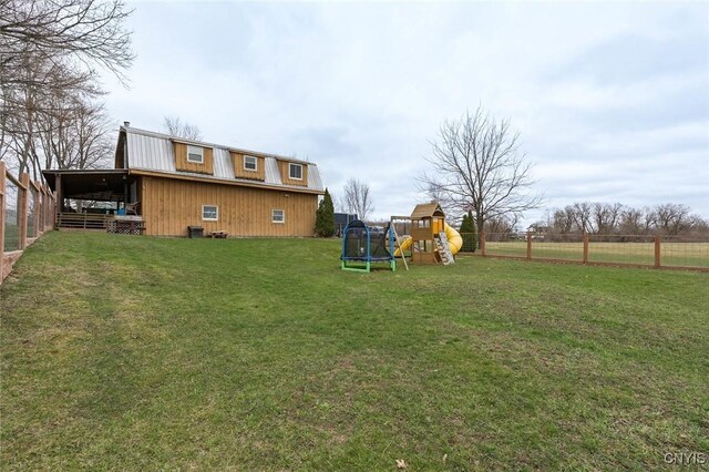 view of yard featuring a trampoline, fence, and a playground