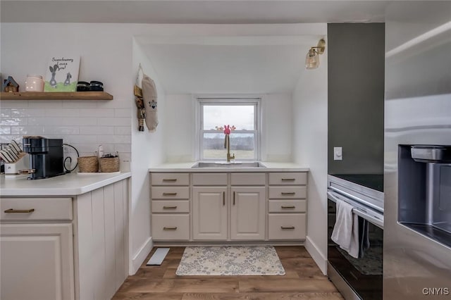 kitchen with tasteful backsplash, wall oven, dark wood-style flooring, and a sink