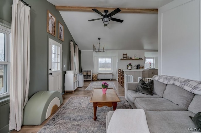 living area featuring beamed ceiling, wood finished floors, high vaulted ceiling, and ceiling fan with notable chandelier