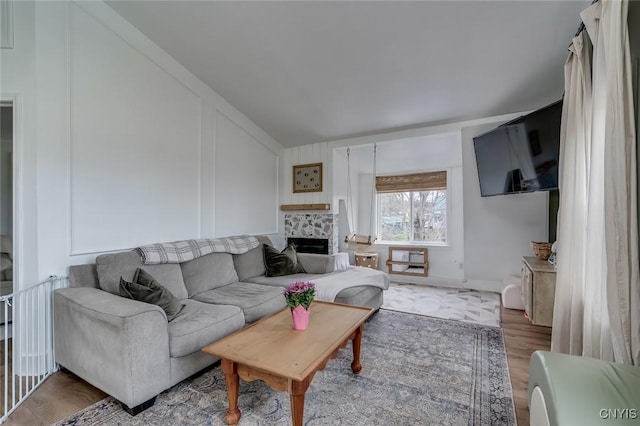 living area with vaulted ceiling, wood finished floors, and a tiled fireplace