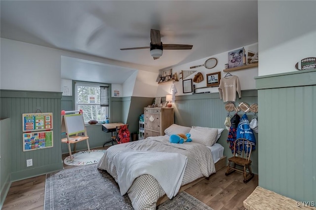 bedroom with wainscoting, a ceiling fan, and wood finished floors