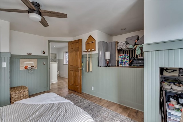 bedroom featuring wainscoting, ceiling fan, baseboards, and wood finished floors