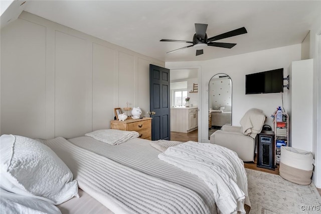 bedroom featuring a decorative wall, light wood finished floors, and ceiling fan