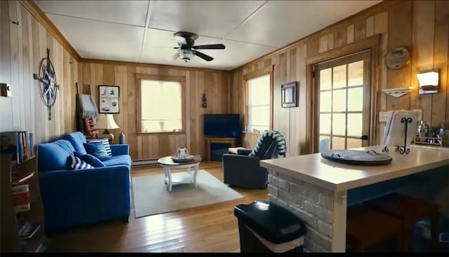living room featuring a baseboard heating unit, wooden walls, wood finished floors, and ceiling fan