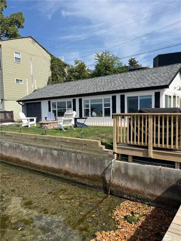 rear view of house featuring a yard and roof with shingles