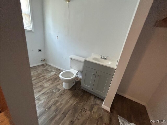 bathroom with baseboards, wood finished floors, vanity, and toilet