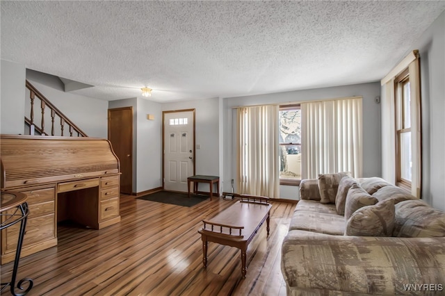 living area with dark wood finished floors, a textured ceiling, and baseboards