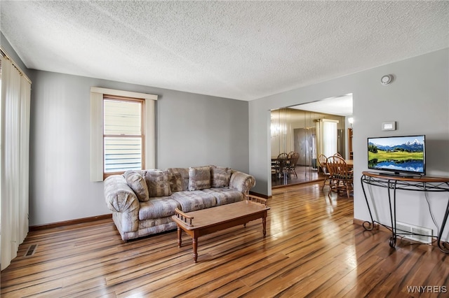 living area featuring wood finished floors, visible vents, baseboards, a chandelier, and a textured ceiling