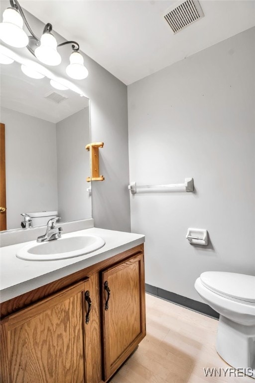 bathroom featuring baseboards, visible vents, toilet, and vanity