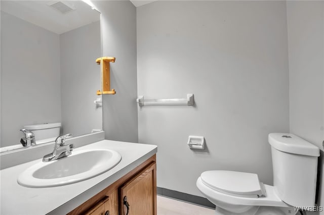 half bathroom featuring toilet, vanity, and visible vents
