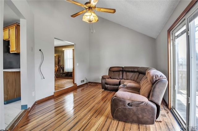 living room featuring vaulted ceiling, baseboards, light wood-style floors, and a ceiling fan