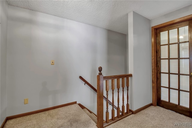 stairs featuring carpet floors, a textured ceiling, and baseboards