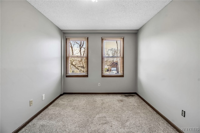 spare room with light carpet, baseboards, and a textured ceiling