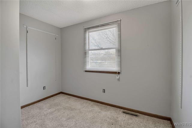 carpeted spare room with baseboards, a textured ceiling, and visible vents