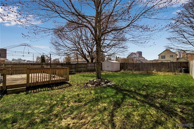 view of yard featuring a fenced backyard, a storage unit, an outdoor structure, and a deck