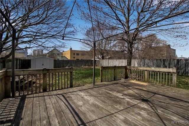 deck featuring a storage shed, a yard, a fenced backyard, and an outdoor structure