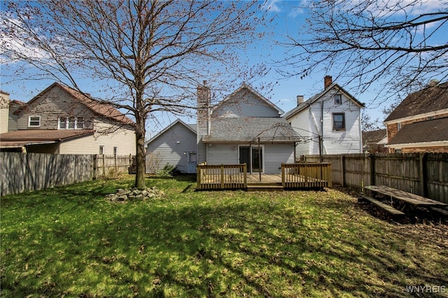 rear view of property with a wooden deck, a lawn, a chimney, and a fenced backyard