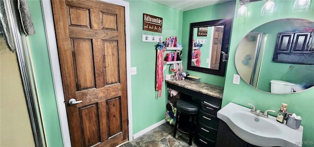 bathroom with stone finish flooring, baseboards, and a sink
