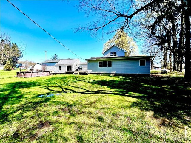 rear view of house featuring a yard and an outdoor pool