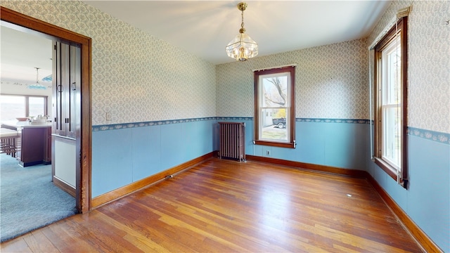 4501 State Route 414, Hector, NY 14818 - unfurnished room with radiator heating unit, a chandelier, wood finished floors, and a wainscoted wall