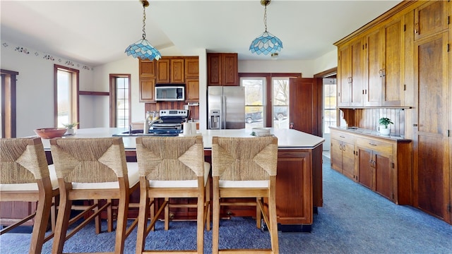 4501 State Route 414, Hector, NY 14818 - kitchen featuring stainless steel appliances, dark colored carpet, brown cabinetry, light countertops, and a breakfast bar area