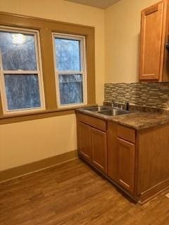 bar with light wood-type flooring, a sink, and decorative backsplash