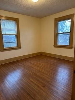 empty room featuring dark wood-style flooring, baseboards, and a textured ceiling