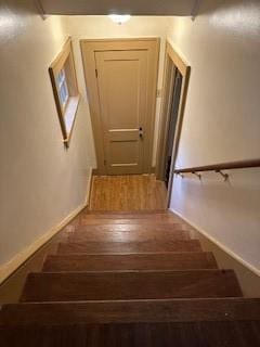 staircase featuring baseboards and wood finished floors