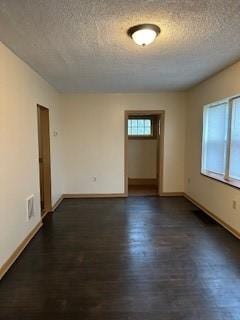 spare room featuring dark wood-type flooring, baseboards, and a textured ceiling