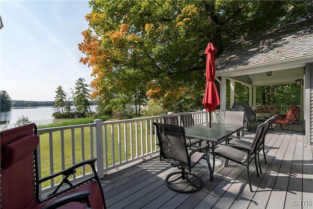 wooden terrace with a lawn, a water view, and outdoor dining space