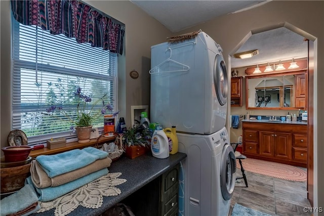 washroom with stacked washer and dryer and a sink