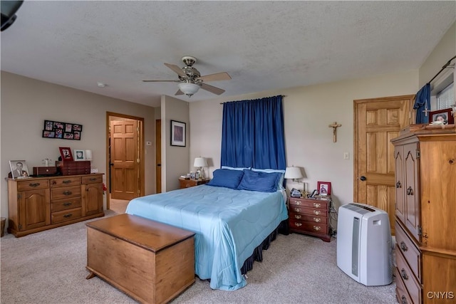 bedroom featuring a ceiling fan, a textured ceiling, and light colored carpet