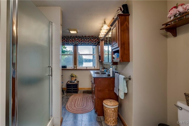 bathroom featuring baseboards, toilet, vanity, and a stall shower