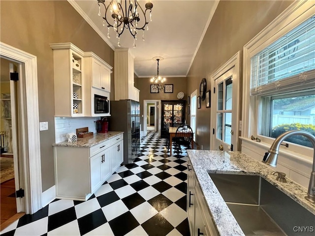 kitchen with a sink, built in microwave, a notable chandelier, stainless steel fridge with ice dispenser, and dark floors