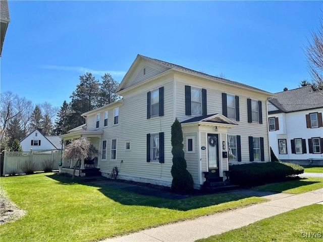view of front facade featuring entry steps, a front lawn, and fence