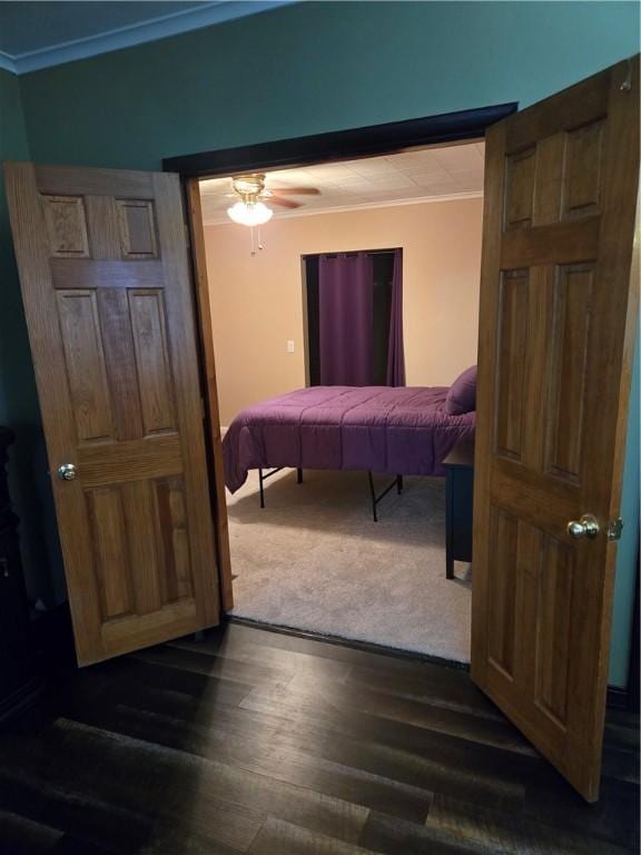 bedroom with dark wood finished floors, crown molding, and ceiling fan