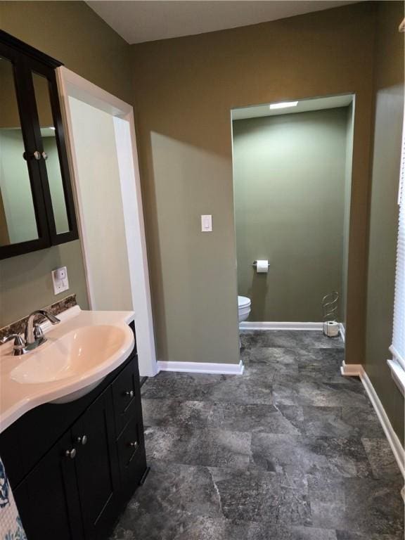 bathroom with baseboards, toilet, and vanity