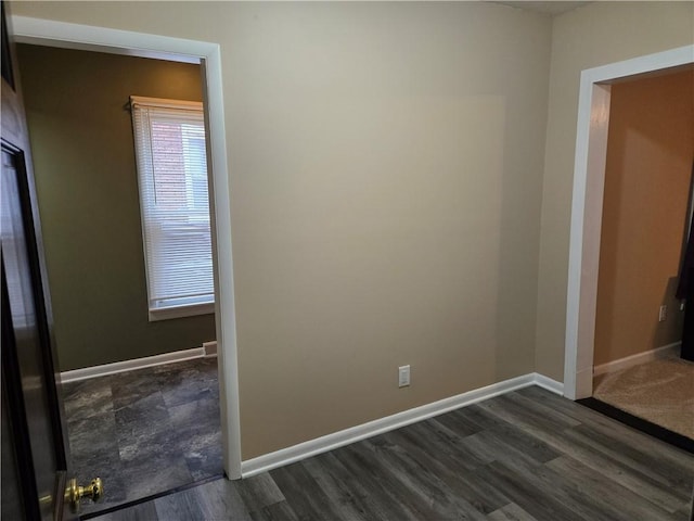 unfurnished bedroom with baseboards and dark wood-type flooring
