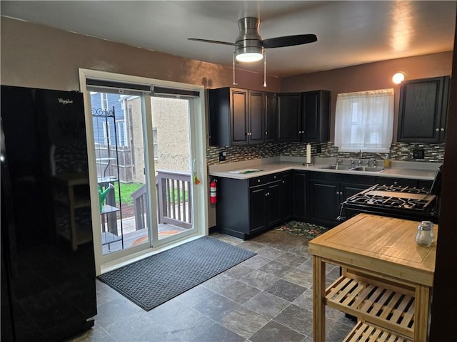 kitchen with light countertops, tasteful backsplash, a sink, and black appliances
