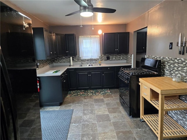 kitchen featuring a ceiling fan, tasteful backsplash, a sink, light countertops, and black gas range oven