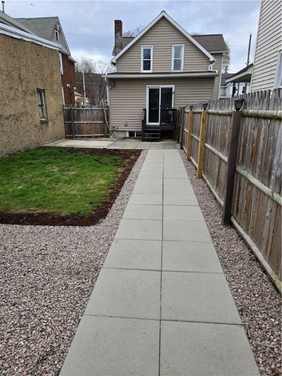 rear view of property with a patio area, a fenced backyard, and a chimney