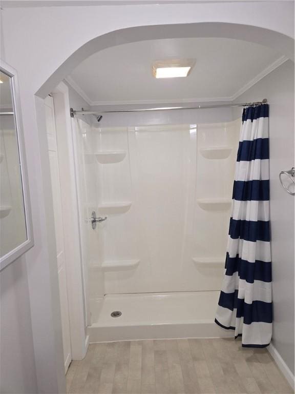 bathroom featuring wood finished floors, a stall shower, and ornamental molding