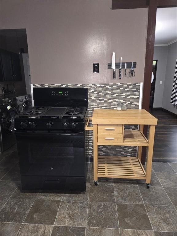 kitchen with backsplash, stone finish flooring, black range with gas cooktop, and crown molding