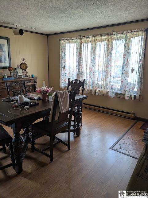dining room featuring a baseboard radiator, wood finished floors, and a textured ceiling