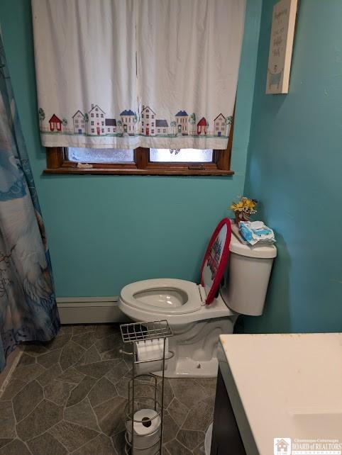 full bathroom with a baseboard radiator, toilet, and vanity