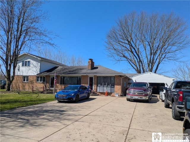 split level home with brick siding, driveway, a front lawn, and a chimney