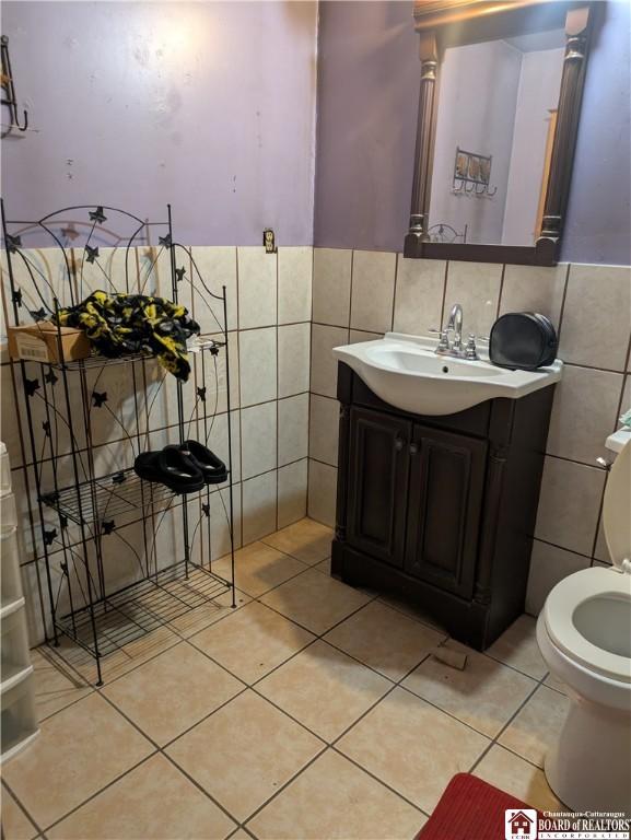 bathroom with tile patterned floors, vanity, tile walls, a wainscoted wall, and toilet