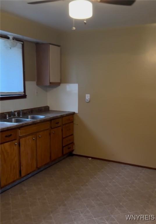396 Guilford St, Buffalo, NY 14211 - kitchen featuring dark countertops, a sink, brown cabinets, light floors, and baseboards